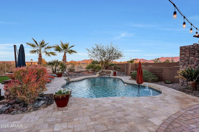 view of pool with pool water feature, a mountain view, and a patio area