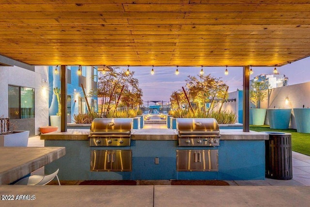 patio terrace at dusk with exterior kitchen and grilling area