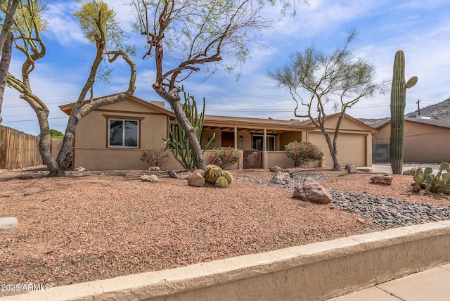 single story home with covered porch, stucco siding, fence, and an attached garage