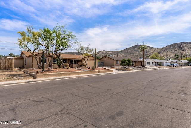 single story home featuring a residential view, stucco siding, fence, and a mountain view