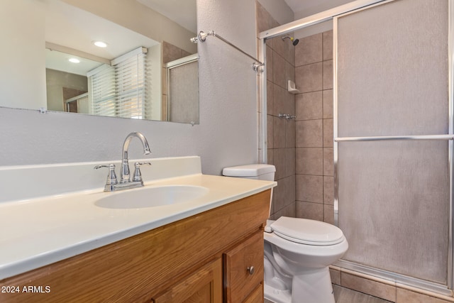 bathroom with vanity, toilet, and a shower with door