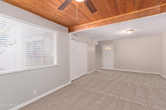 carpeted spare room featuring ceiling fan, beamed ceiling, and wooden ceiling