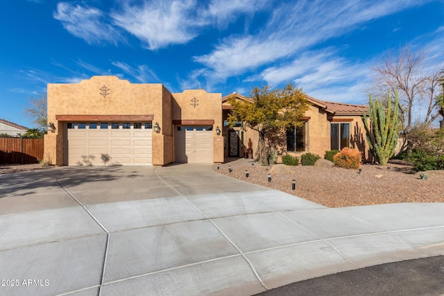 southwest-style home with stucco siding, an attached garage, driveway, and fence