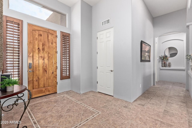 foyer entrance with visible vents and a high ceiling