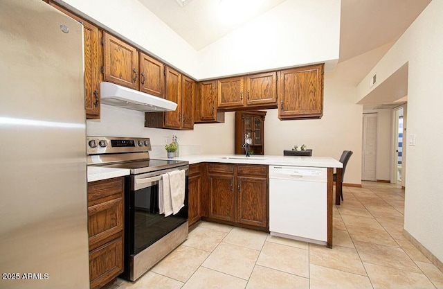 kitchen featuring light tile patterned floors, appliances with stainless steel finishes, kitchen peninsula, and sink