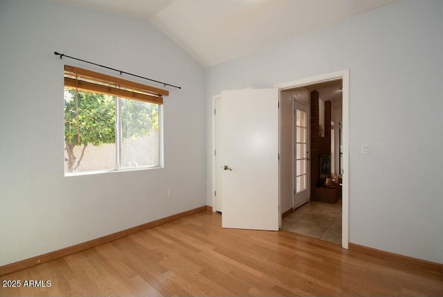 spare room featuring lofted ceiling and light hardwood / wood-style floors