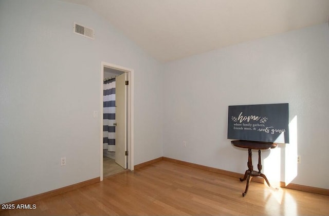 empty room featuring hardwood / wood-style flooring and lofted ceiling