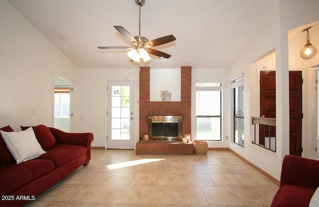 tiled living room with ceiling fan, vaulted ceiling, plenty of natural light, and a brick fireplace