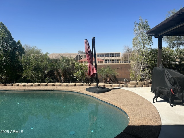 outdoor pool with grilling area, fence, and a patio area