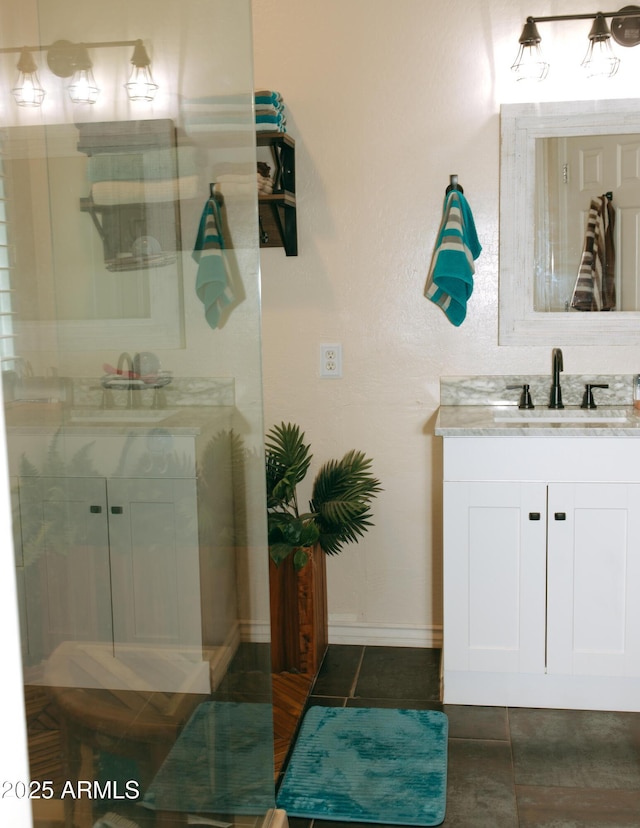 bathroom featuring tile patterned floors, vanity, a shower, and baseboards