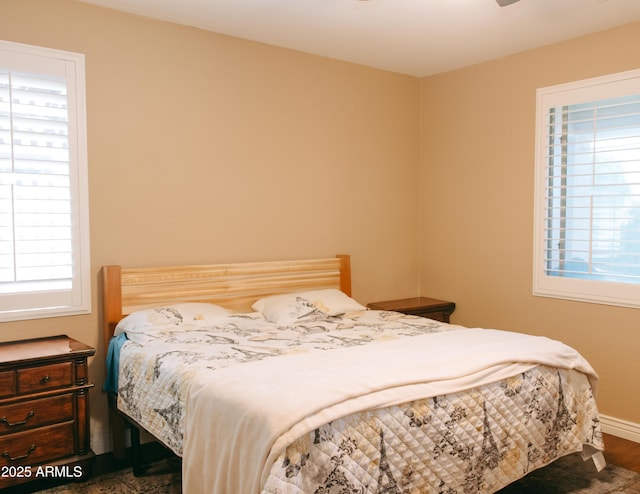 bedroom with multiple windows, wood finished floors, and baseboards