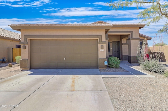 prairie-style home featuring stucco siding, an attached garage, concrete driveway, and fence