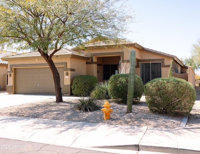 view of front of house with a tiled roof, an attached garage, driveway, and stucco siding