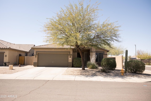 view of front of house with stucco siding, an attached garage, driveway, and fence