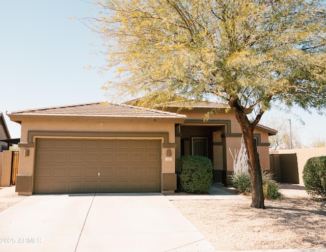 view of front of house featuring stucco siding, driveway, an attached garage, and fence