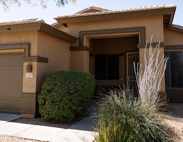 property entrance with a garage and stucco siding