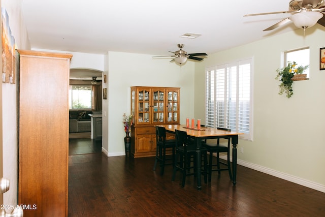 dining space with visible vents, dark wood finished floors, arched walkways, baseboards, and ceiling fan