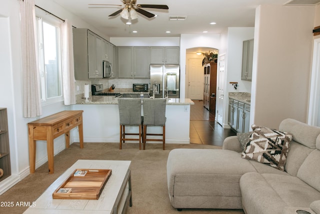 kitchen featuring visible vents, gray cabinetry, open floor plan, a peninsula, and stainless steel appliances