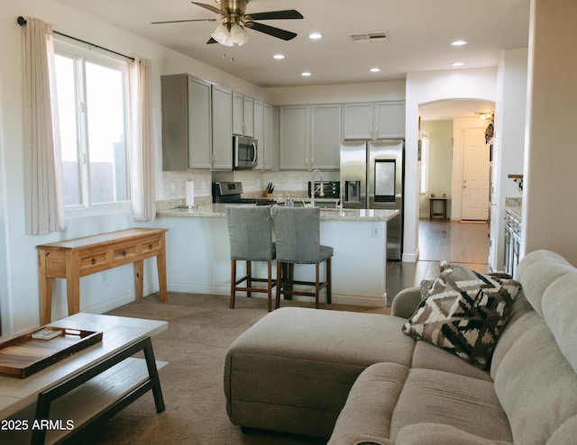 living area featuring visible vents, recessed lighting, arched walkways, baseboards, and ceiling fan