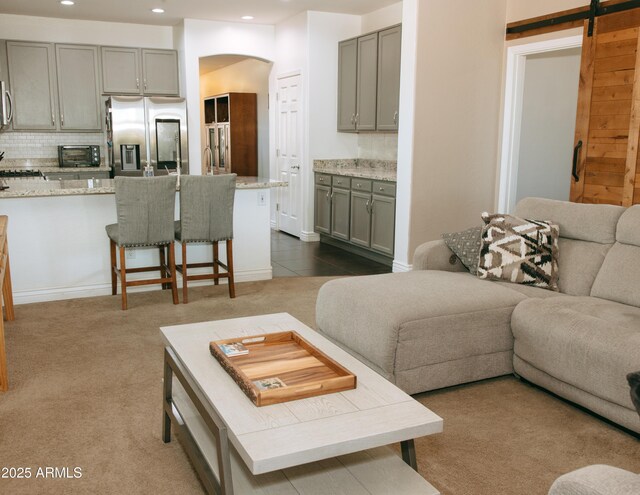 living area with a toaster, dark carpet, a barn door, recessed lighting, and arched walkways