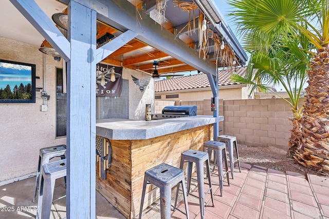 view of patio featuring grilling area, exterior bar, and ceiling fan