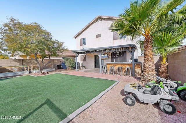 rear view of property featuring a patio, an outdoor bar, and a lawn