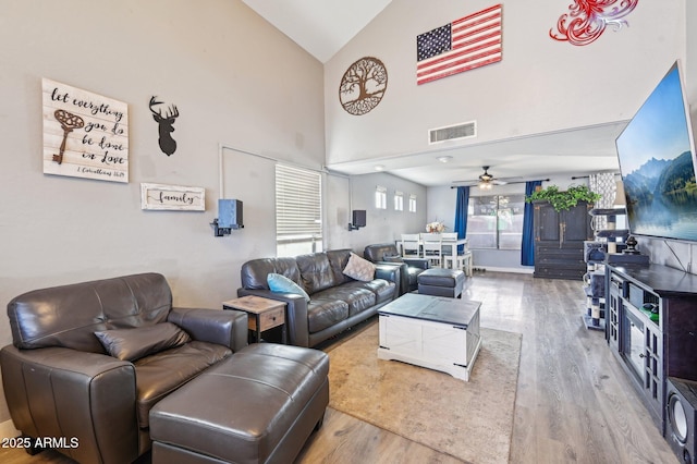 living room with hardwood / wood-style flooring, ceiling fan, and high vaulted ceiling