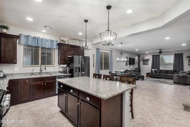 kitchen with visible vents, a kitchen bar, a sink, a center island, and appliances with stainless steel finishes