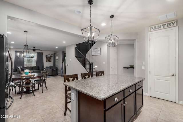 kitchen with visible vents, a breakfast bar, freestanding refrigerator, recessed lighting, and dark brown cabinets