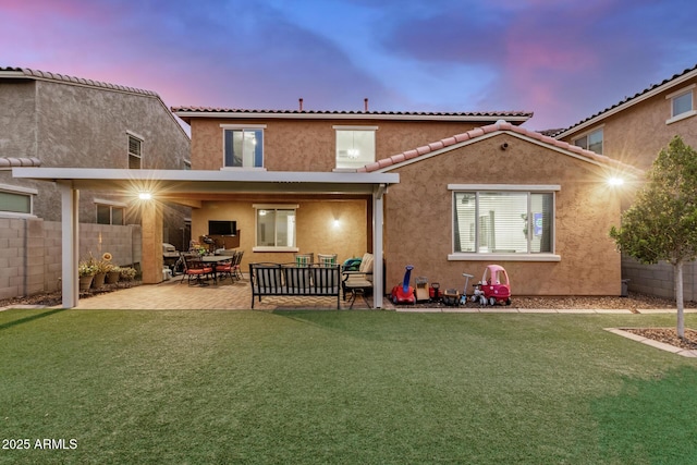 rear view of property with stucco siding, a patio, a lawn, and fence