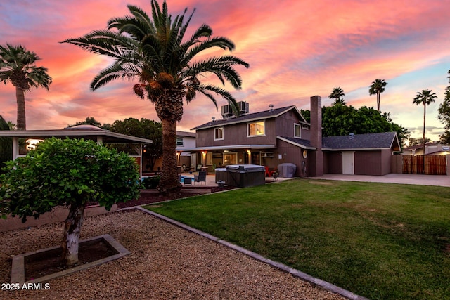 3377 W Grandview Rd, Phoenix, AZ 85053 - back of property at dusk featuring fence, a hot tub, concrete driveway, a lawn, and a patio