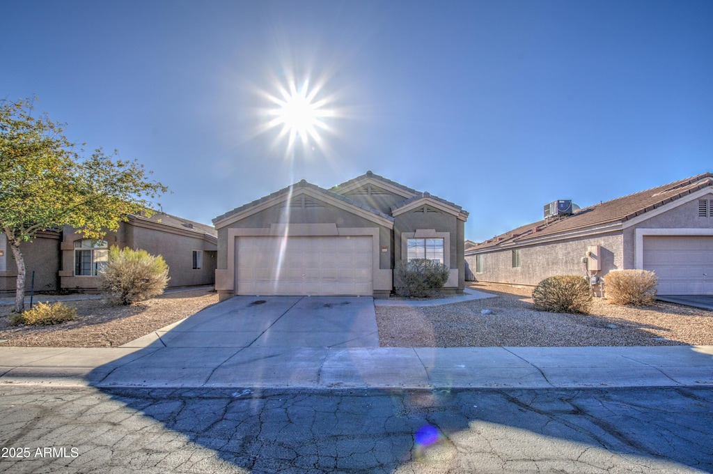 single story home featuring cooling unit and a garage