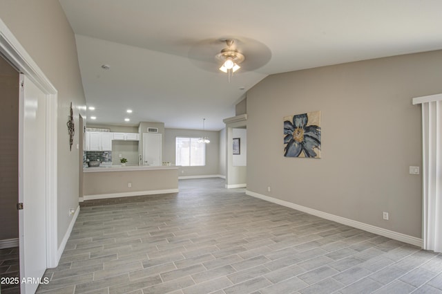 unfurnished living room with lofted ceiling, ceiling fan with notable chandelier, and light hardwood / wood-style flooring