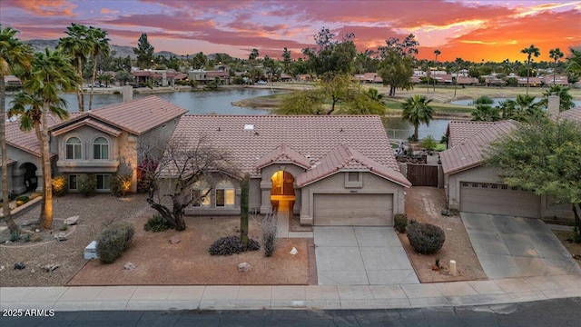 view of front of property featuring driveway, a water view, a tile roof, and stucco siding