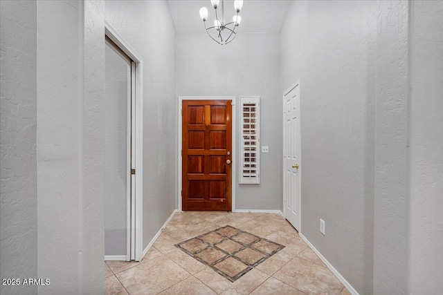 entryway with baseboards, light tile patterned floors, and a notable chandelier