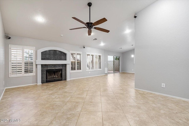 unfurnished living room featuring ceiling fan, a fireplace, a wealth of natural light, and baseboards