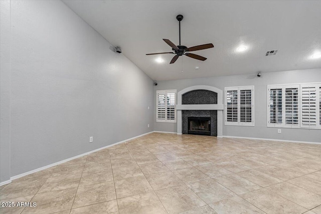 unfurnished living room featuring visible vents, vaulted ceiling, ceiling fan, a tile fireplace, and baseboards