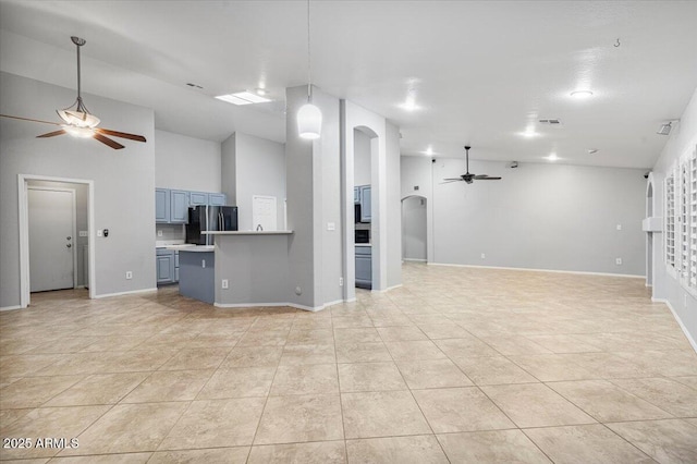 unfurnished living room with light tile patterned floors, arched walkways, a ceiling fan, and baseboards