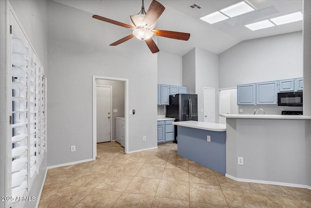 kitchen featuring freestanding refrigerator, light countertops, blue cabinetry, washing machine and dryer, and black microwave