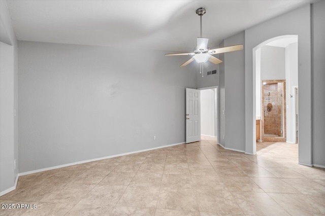 unfurnished bedroom featuring arched walkways, connected bathroom, a towering ceiling, visible vents, and baseboards