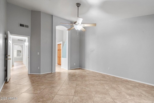 empty room with light tile patterned floors, visible vents, arched walkways, baseboards, and ceiling fan