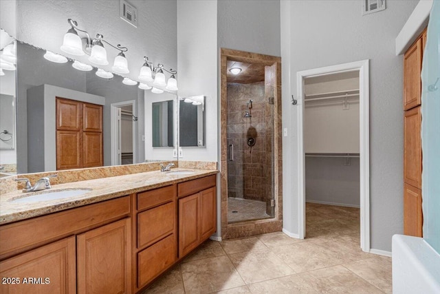 bathroom with a stall shower, visible vents, and a sink