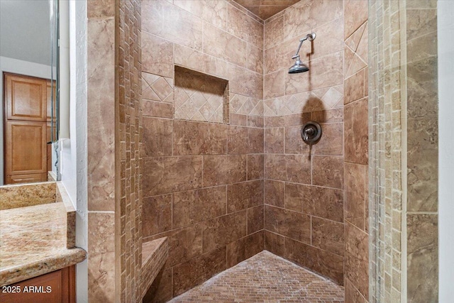 full bathroom with tiled shower and vanity