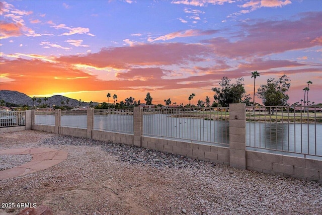 property view of water featuring fence and a mountain view