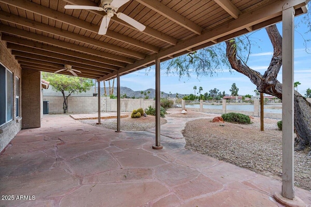 view of patio / terrace featuring ceiling fan, fence, a mountain view, and central AC