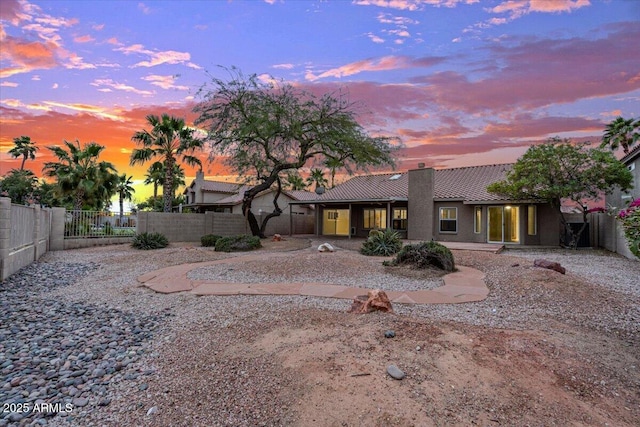 back of property with fence private yard, a chimney, stucco siding, and a tiled roof