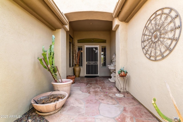 view of exterior entry with stucco siding and a patio area