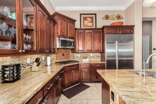 kitchen featuring ornamental molding, light stone countertops, tasteful backsplash, a sink, and stainless steel appliances