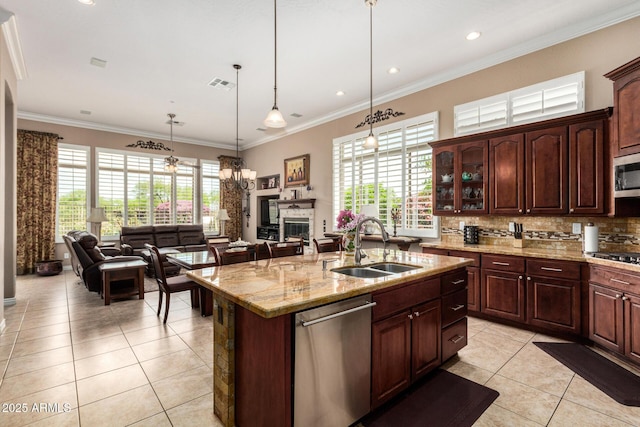 kitchen featuring light tile patterned flooring, appliances with stainless steel finishes, a sink, open floor plan, and backsplash