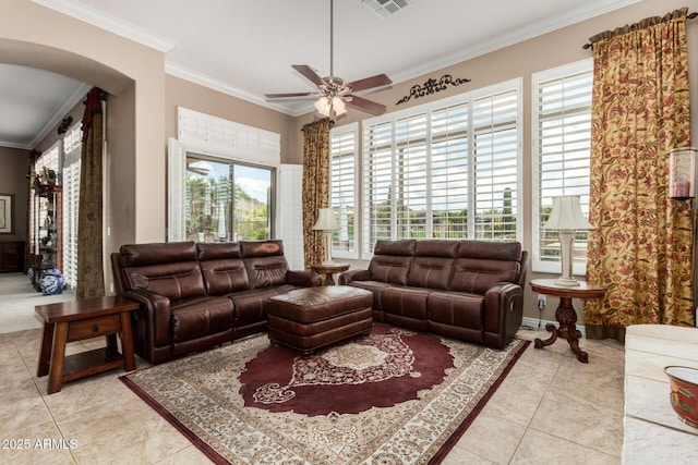 living area featuring ceiling fan, arched walkways, light tile patterned floors, visible vents, and ornamental molding